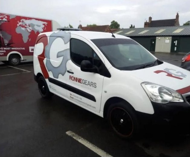 A white signwritten van parked on wet tarmac, with a large red and grey gear-wheel monogram on the side panel and the business name along the lower door.